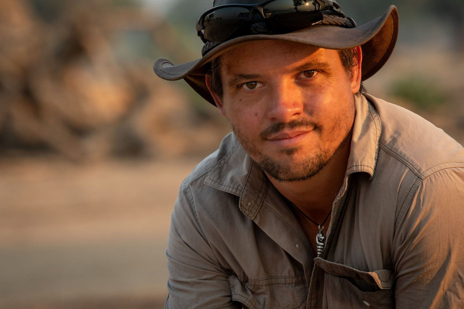 Man wearing a safari hat and brown shirt in a natural setting